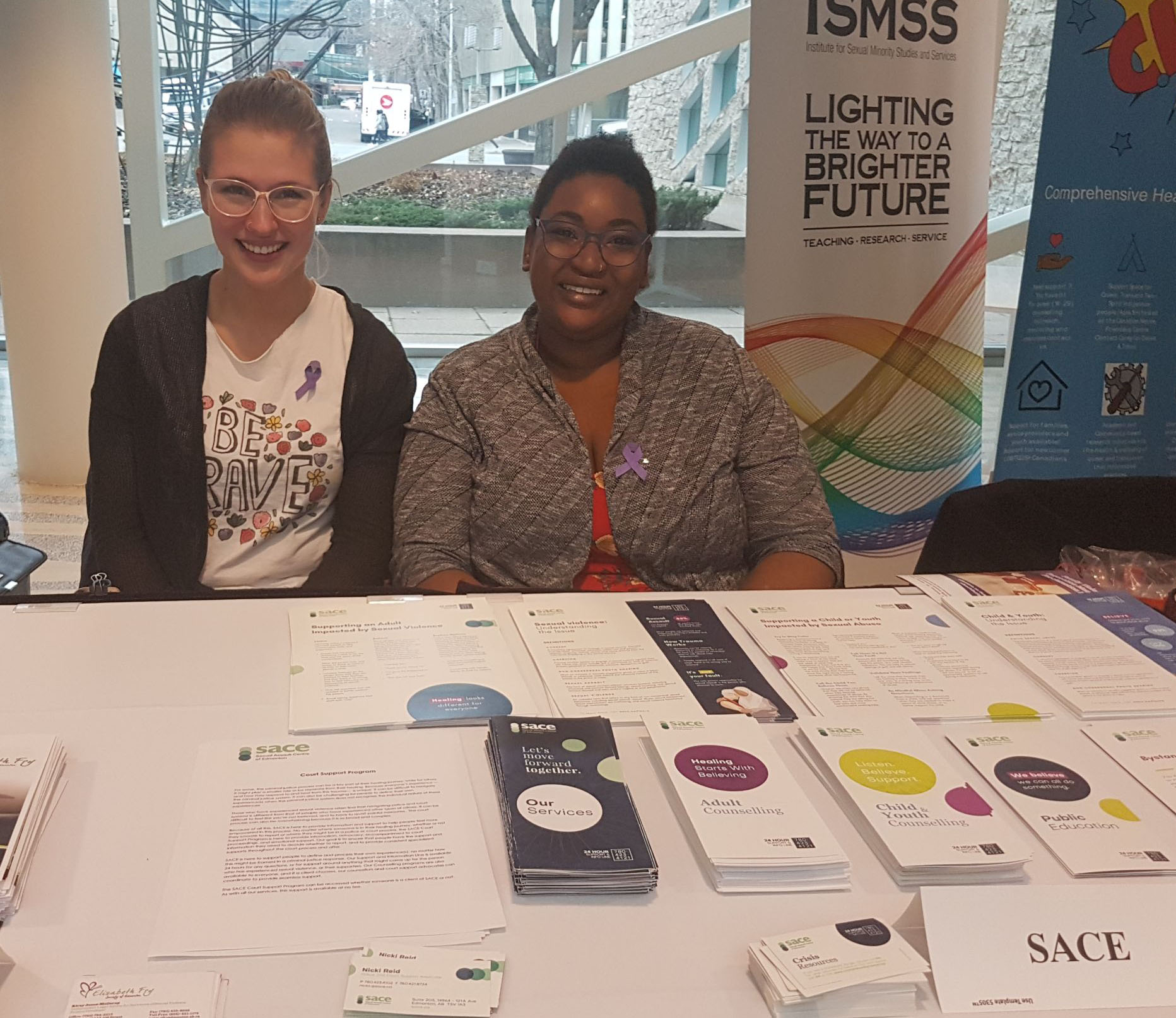 SACE Police and Court Support services advocate sits at a booth display for family violence month