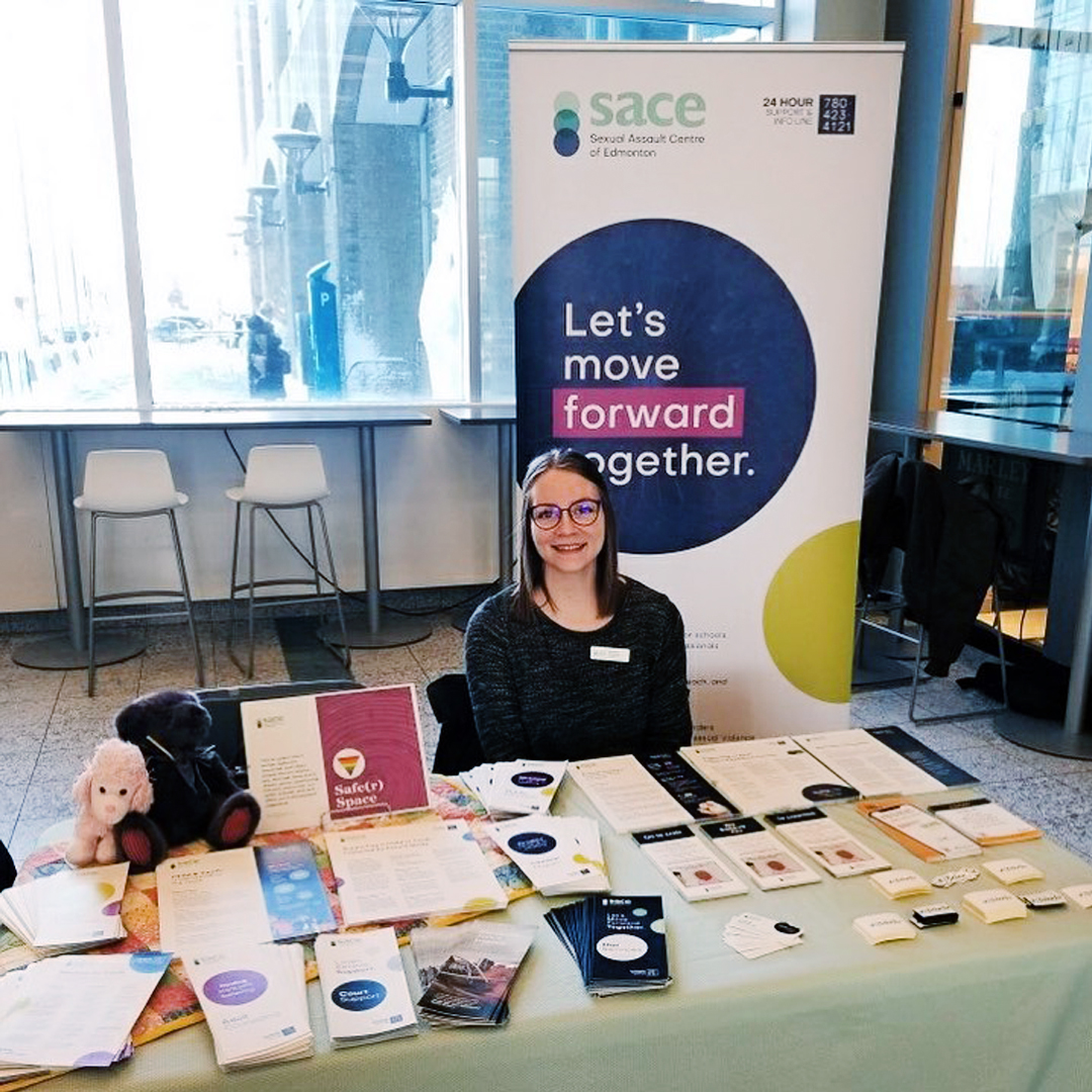 A SACE public educator sits at a community resources table to promote SACE services and print materials