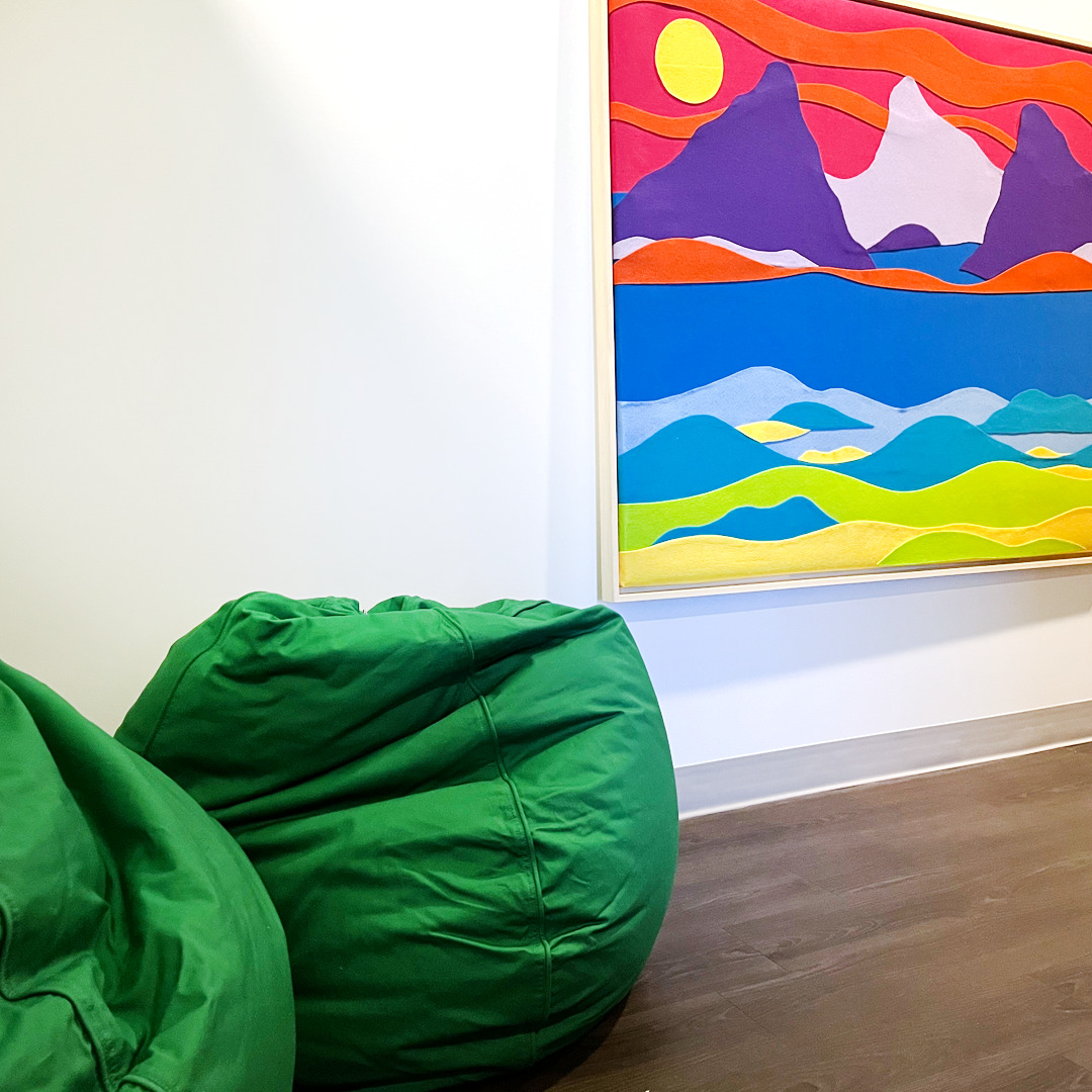 SACE playroom with two green bean bags in front of a quilted picture of mountains.